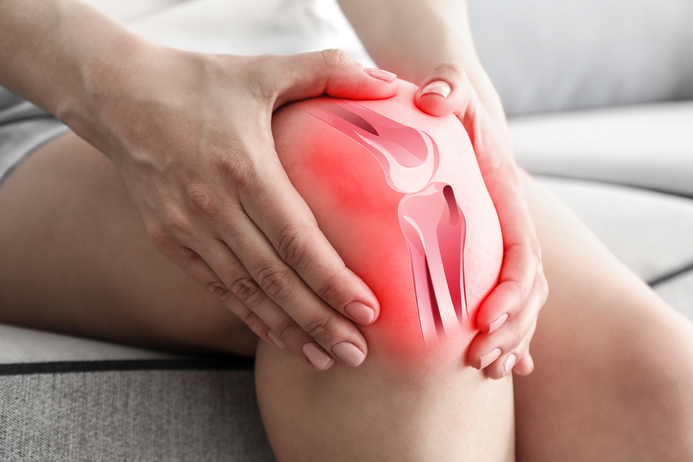 woman holding painful knee with red diagram of inflamed joint