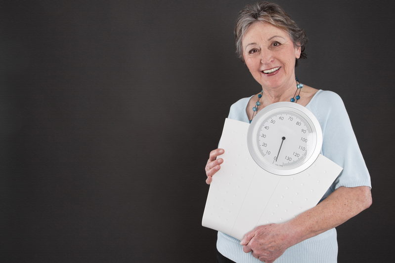 senior woman holding scale after weight loss