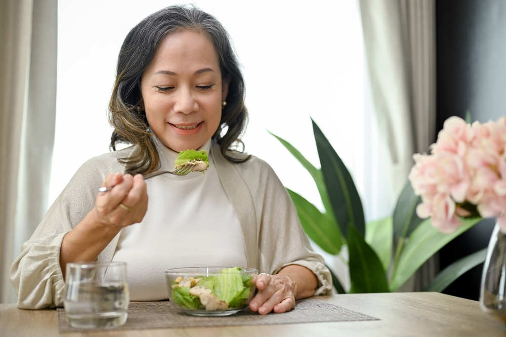 older woman sitting at table eating salad